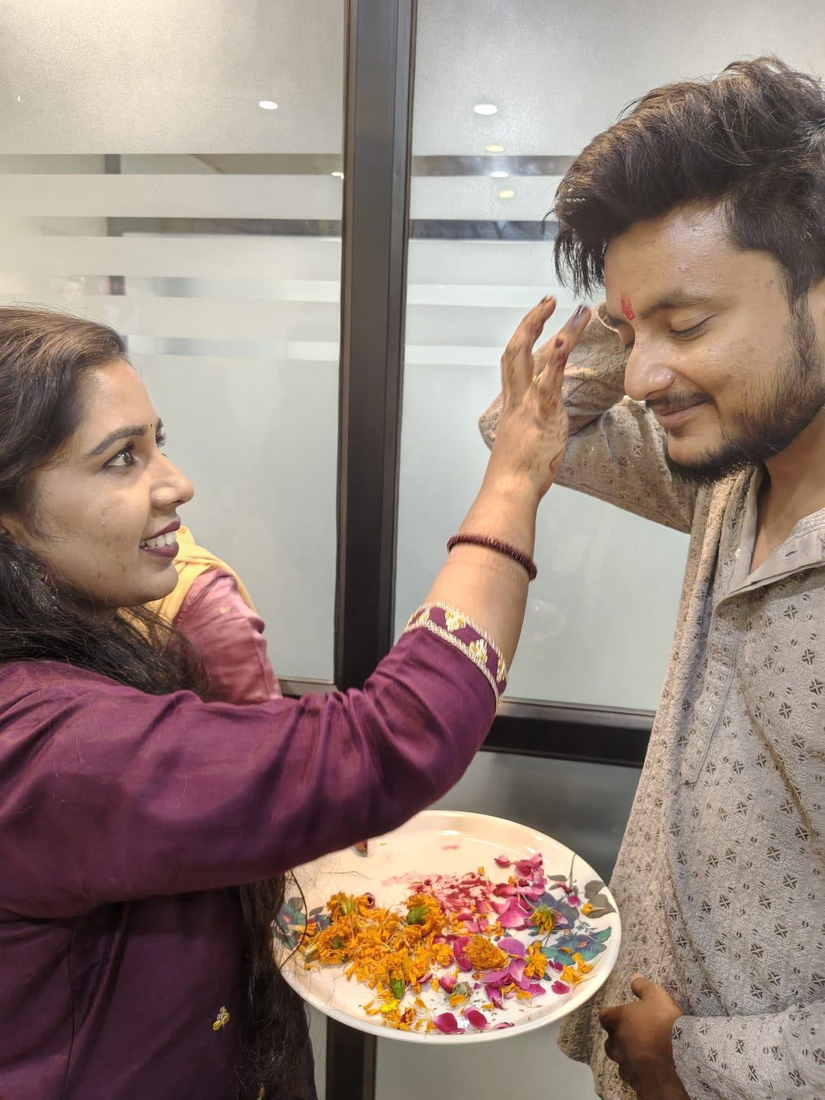 A TradeAura team member applying tilak to a colleague during the Ganesh Chaturthi puja