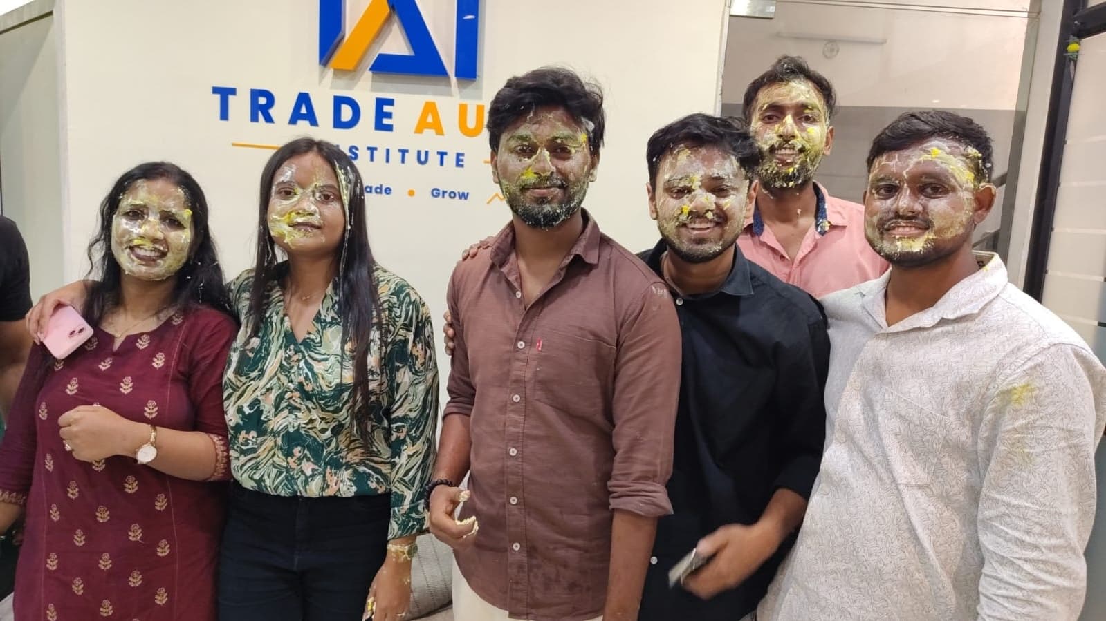 TradeAura students cutting a birthday cake surrounded by friends and mentors