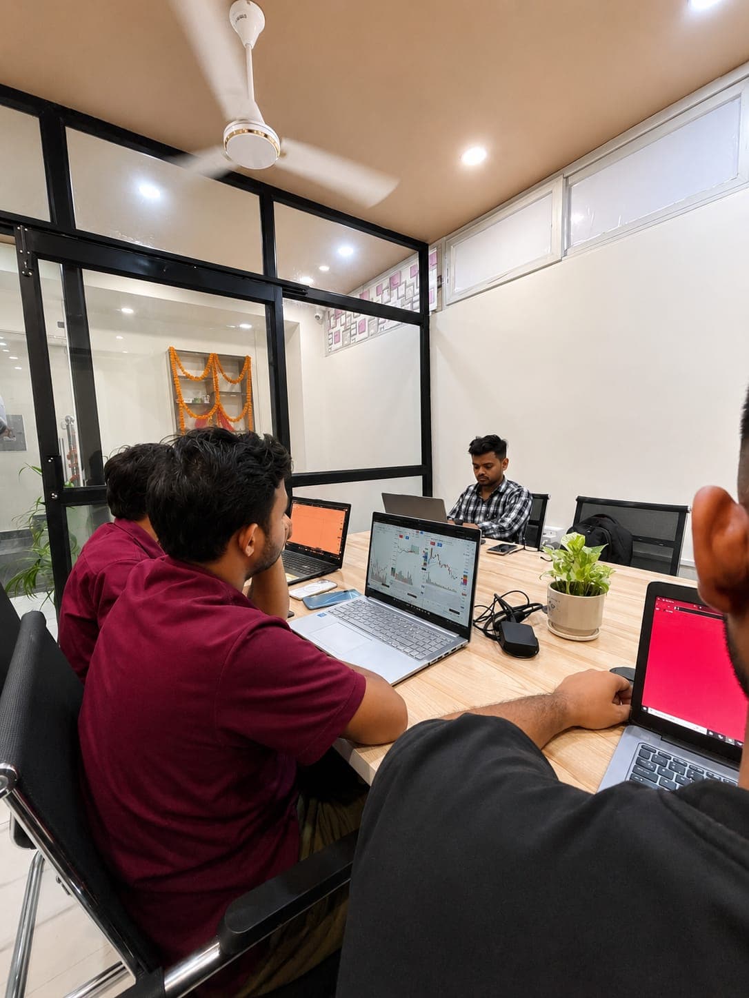 Students studying trading charts on their laptops inside a glass-walled classroom at TradeAura Institute